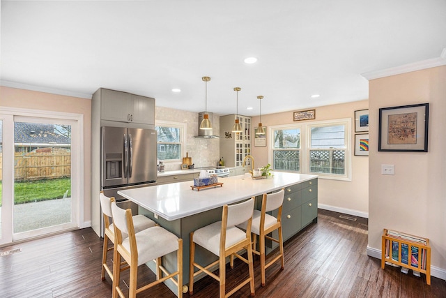 kitchen with gray cabinets, light countertops, stainless steel fridge with ice dispenser, baseboards, and wall chimney exhaust hood
