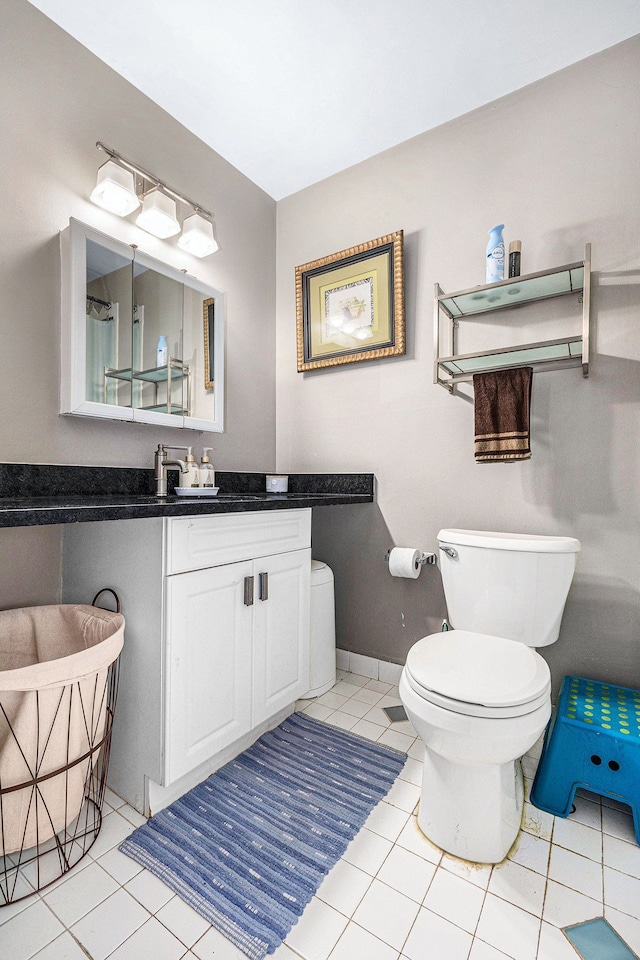 bathroom featuring tile patterned flooring, baseboards, toilet, and vanity
