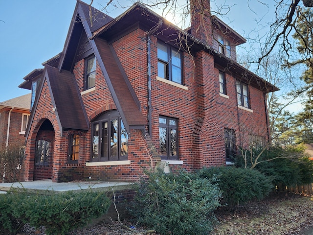 view of property exterior with a chimney and brick siding