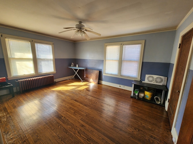 unfurnished room featuring a ceiling fan, hardwood / wood-style flooring, baseboards, radiator, and ornamental molding