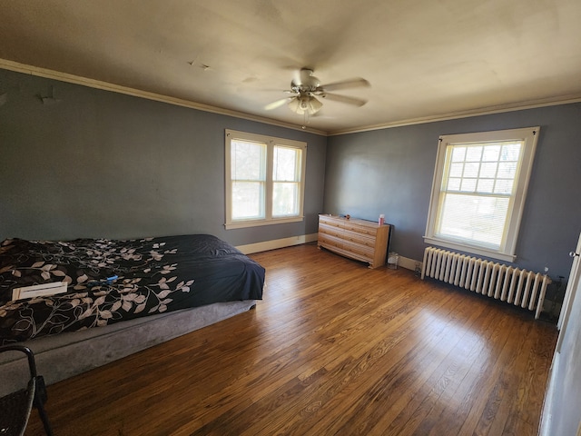 bedroom featuring crown molding, baseboards, wood finished floors, and radiator