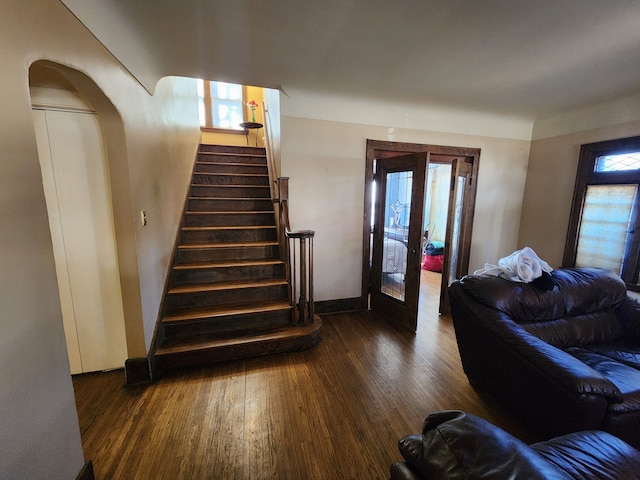 interior space with french doors, dark wood-style flooring, arched walkways, baseboards, and stairs
