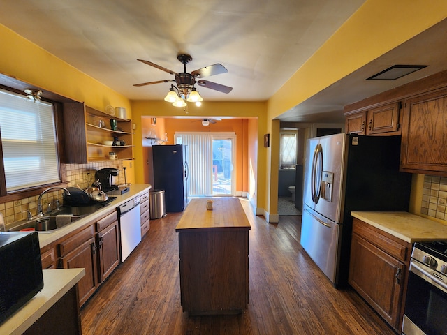kitchen featuring stainless steel appliances, tasteful backsplash, a sink, and a center island
