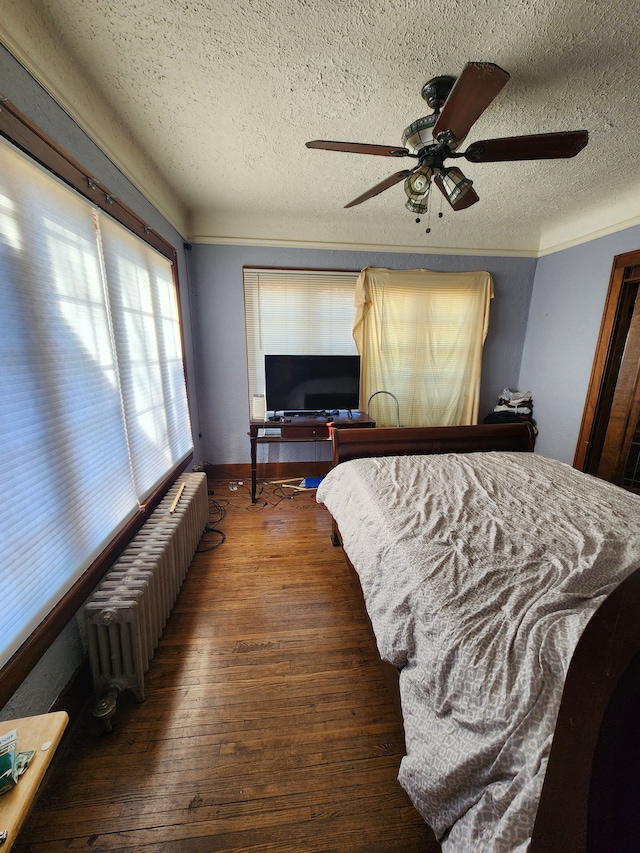 bedroom with hardwood / wood-style floors, radiator, ceiling fan, and a textured ceiling