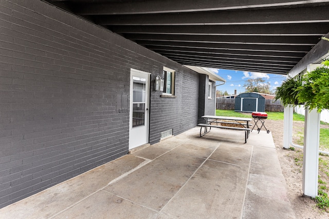 view of patio featuring a storage shed, fence, and an outbuilding