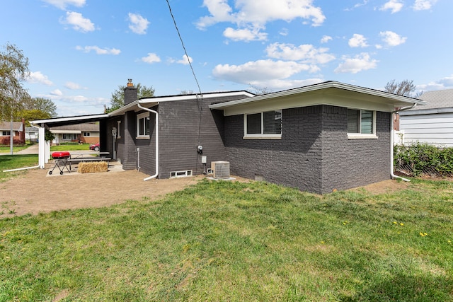 rear view of property with a lawn, central AC unit, a chimney, and a patio