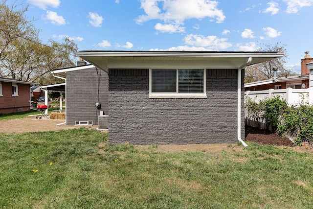 view of side of home featuring fence and a yard