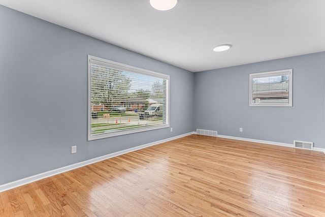 empty room featuring baseboards, light wood-style flooring, and visible vents