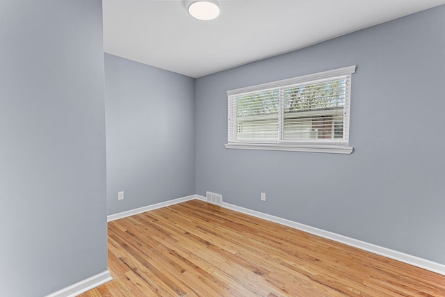 empty room with baseboards, light wood finished floors, and visible vents