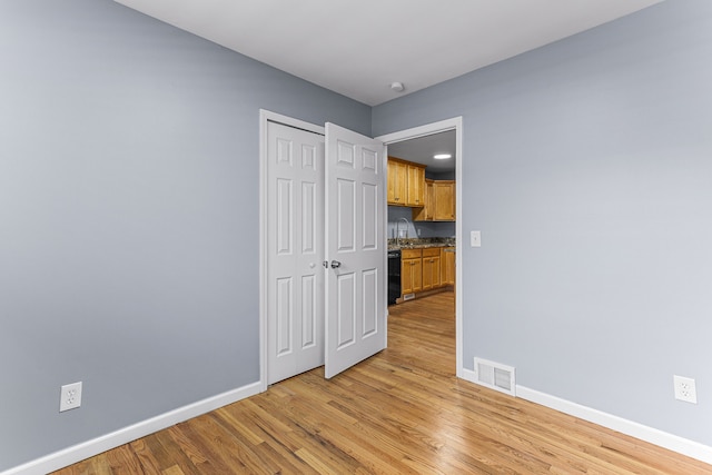 empty room with baseboards, visible vents, a sink, and light wood-type flooring