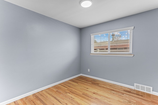 empty room featuring visible vents, baseboards, and wood finished floors