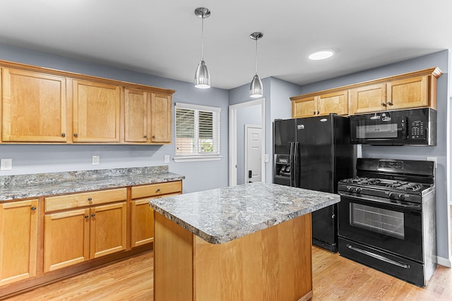 kitchen featuring light wood-style floors, a center island, hanging light fixtures, and black appliances