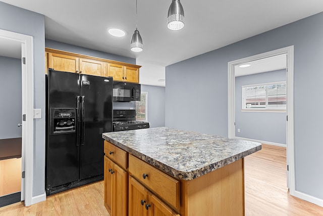 kitchen featuring baseboards, light wood finished floors, black appliances, and a center island