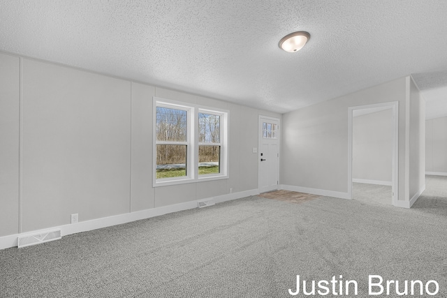 spare room with a textured ceiling, visible vents, carpet, and baseboards