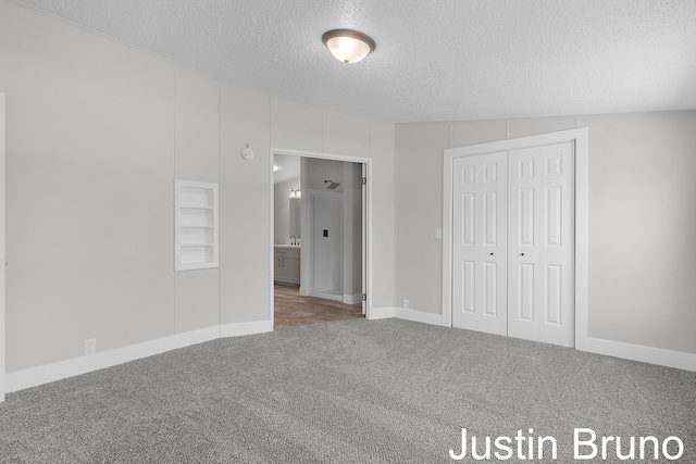 unfurnished bedroom with a textured ceiling, carpet flooring, a closet, and baseboards