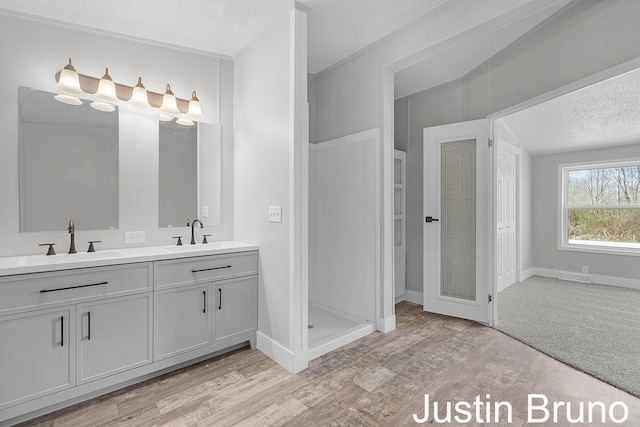 full bath with a textured ceiling, a sink, double vanity, and wood finished floors