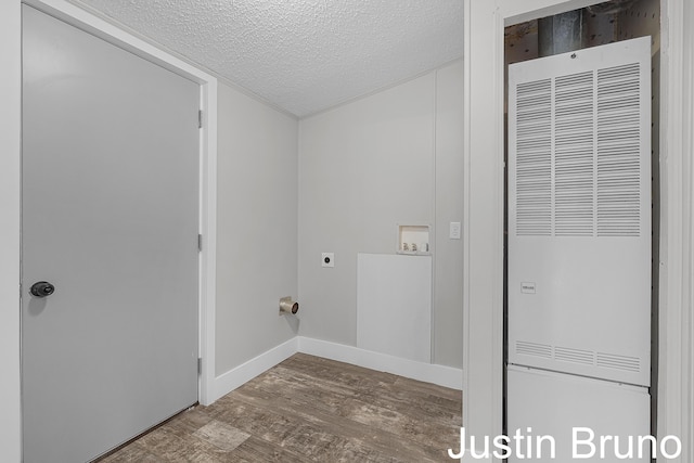 laundry area with wood finished floors, laundry area, hookup for an electric dryer, a textured ceiling, and a heating unit