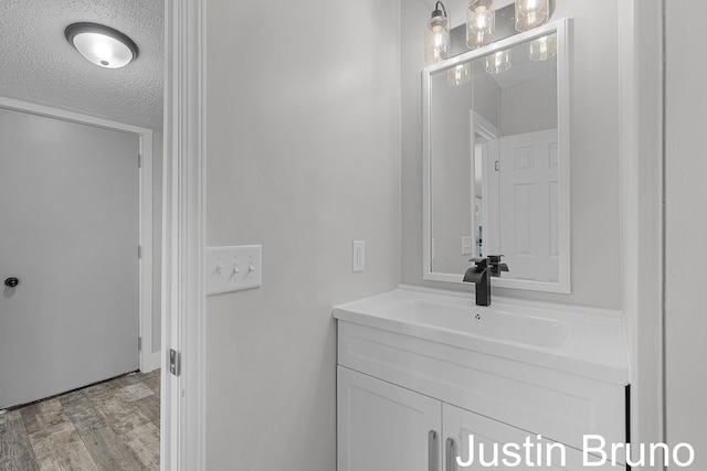 bathroom with wood finished floors, a textured ceiling, and vanity