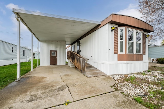 manufactured / mobile home featuring a carport, driveway, and a front yard