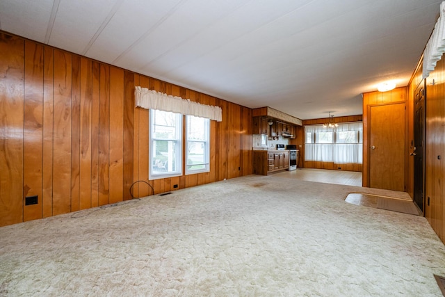 unfurnished living room with wood walls and light carpet