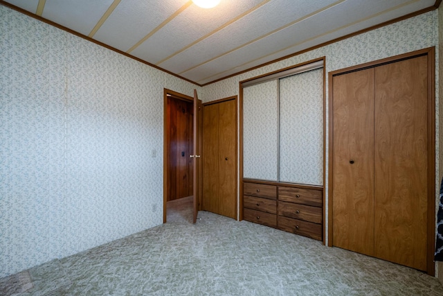 unfurnished bedroom featuring ornamental molding, a closet, wallpapered walls, and carpet floors