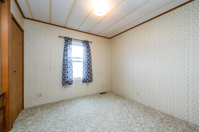 carpeted spare room with visible vents, wallpapered walls, and crown molding