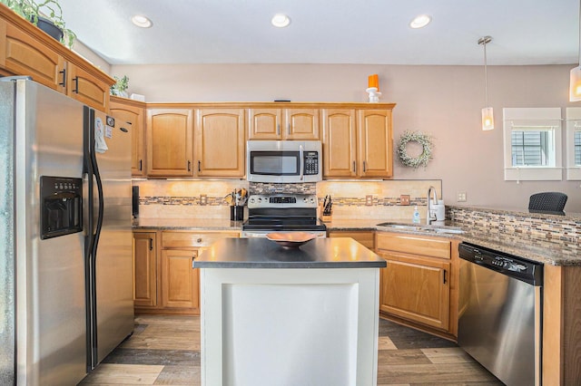 kitchen with appliances with stainless steel finishes, wood finished floors, decorative backsplash, and a sink