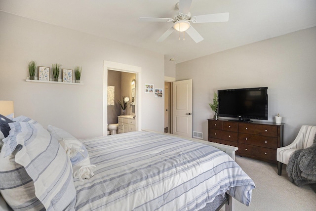 bedroom featuring ceiling fan, light colored carpet, visible vents, and connected bathroom