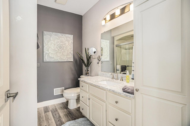 bathroom featuring a shower stall, vanity, toilet, visible vents, and wood finished floors