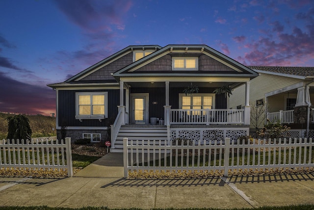 view of front of house featuring a porch, board and batten siding, a fenced front yard, and stairs