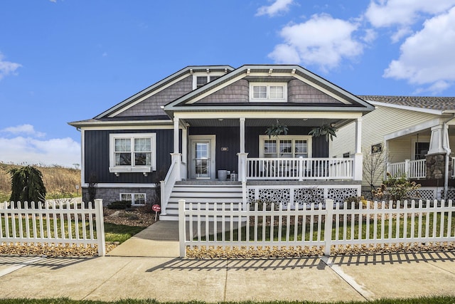 view of front facade with board and batten siding, a porch, and a fenced front yard