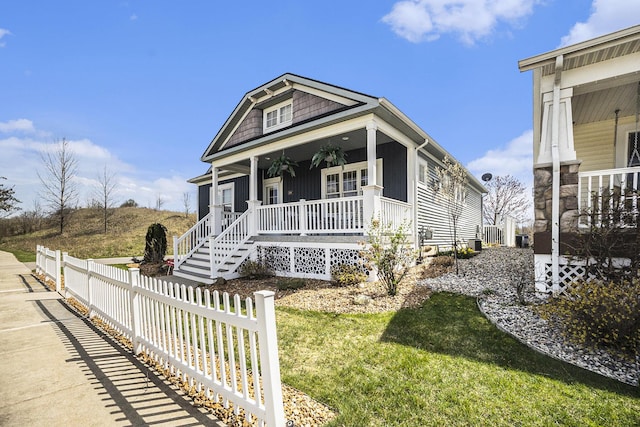 view of front of house featuring a front lawn, stairway, covered porch, and fence