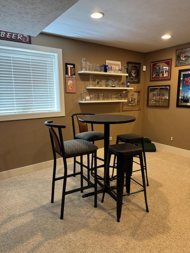 bar with baseboards, recessed lighting, a bar, and carpet flooring