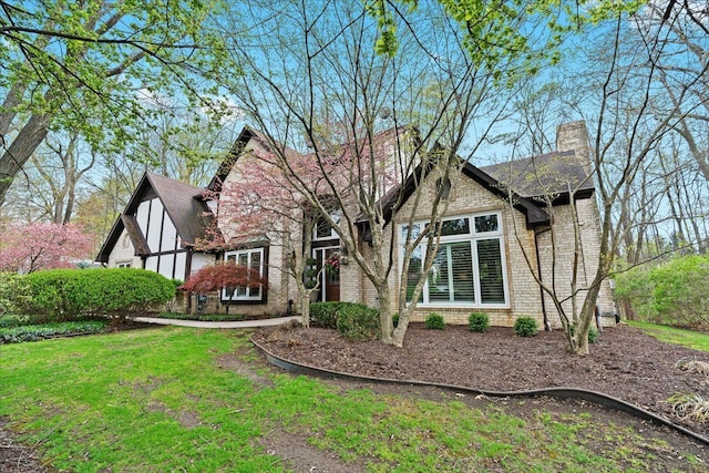 rear view of house with brick siding, a chimney, and a yard