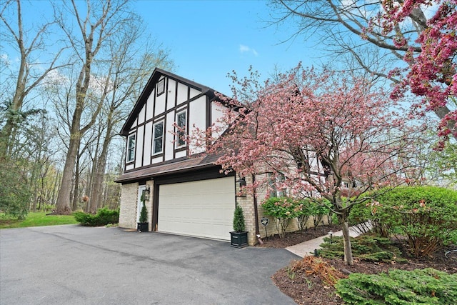 view of home's exterior featuring driveway, a garage, stucco siding, and brick siding