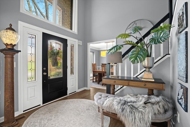 foyer entrance featuring a high ceiling, baseboards, and dark wood finished floors