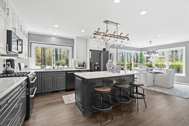kitchen featuring appliances with stainless steel finishes, a kitchen island, backsplash, a kitchen bar, and a chandelier