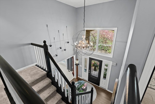 foyer with a chandelier, a high ceiling, baseboards, wood finished floors, and stairway