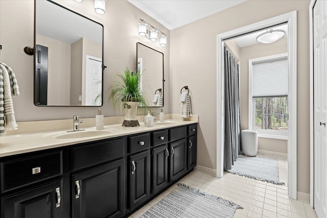 bathroom with double vanity, tile patterned floors, and baseboards