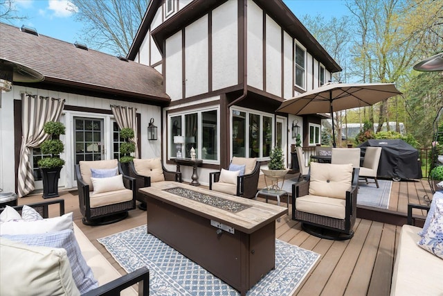 wooden terrace with an outdoor living space with a fire pit and area for grilling