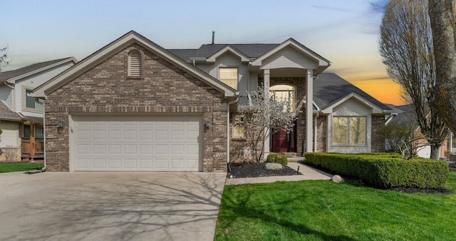 traditional home featuring concrete driveway, a front yard, an attached garage, and brick siding