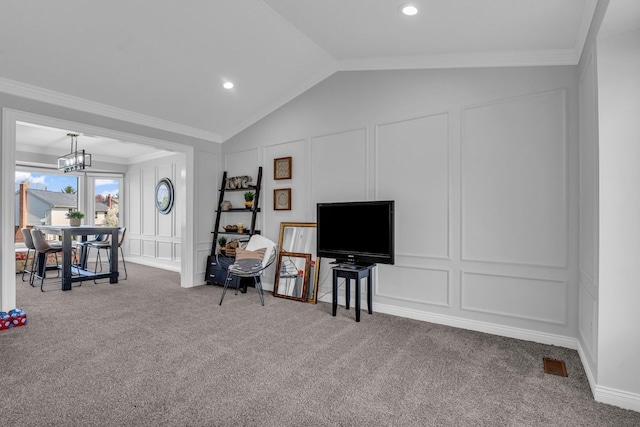 living area with vaulted ceiling, ornamental molding, carpet flooring, and a decorative wall