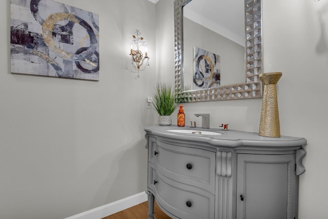 bathroom featuring wood finished floors, vanity, crown molding, and baseboards
