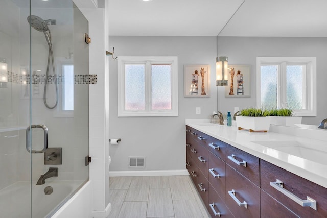 full bath with baseboards, visible vents, double vanity, and a sink