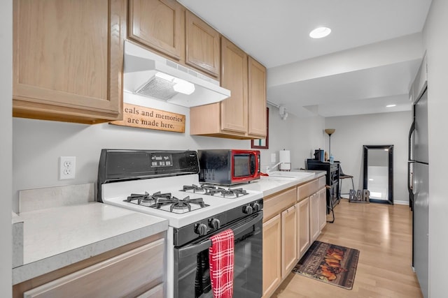 kitchen with light wood-style flooring, light countertops, white range with gas cooktop, under cabinet range hood, and light brown cabinetry