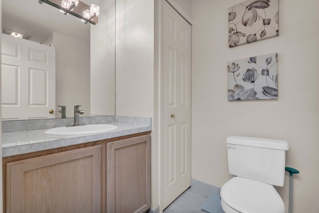 half bath featuring toilet, tile patterned flooring, and vanity