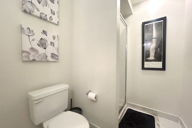 bathroom featuring baseboards, a walk in shower, and toilet