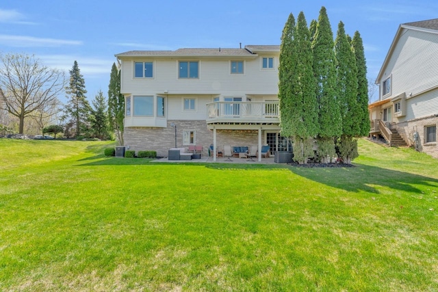 back of property with a patio, stairway, a lawn, stone siding, and a deck