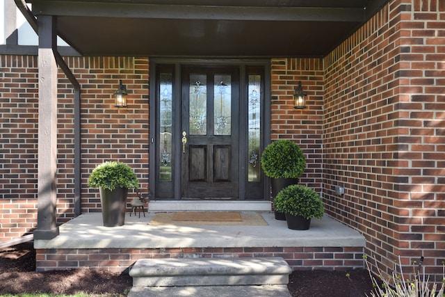 view of exterior entry featuring covered porch and brick siding