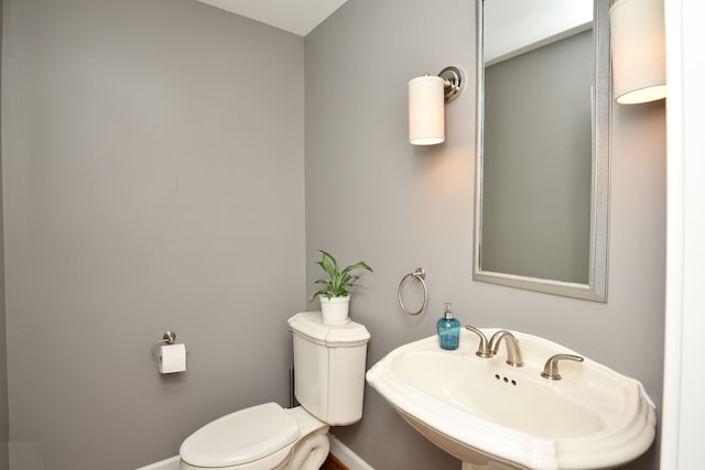 half bath with a sink, baseboards, and toilet